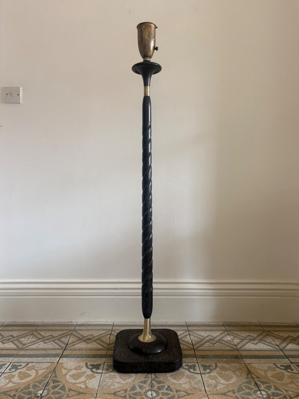 A French 1920s ebonised floor lamp featuring a carved barley twist column on a square base with a brass socket fitting.