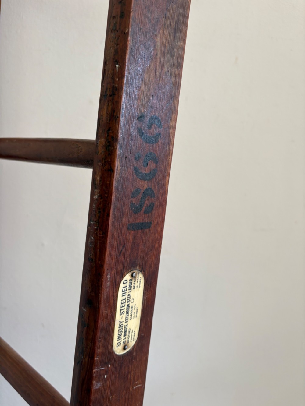 A tall early 20th-century pitch pine and elm library ladder with turned wooden rungs and a padded upper rail leaning against a white wall. View VII