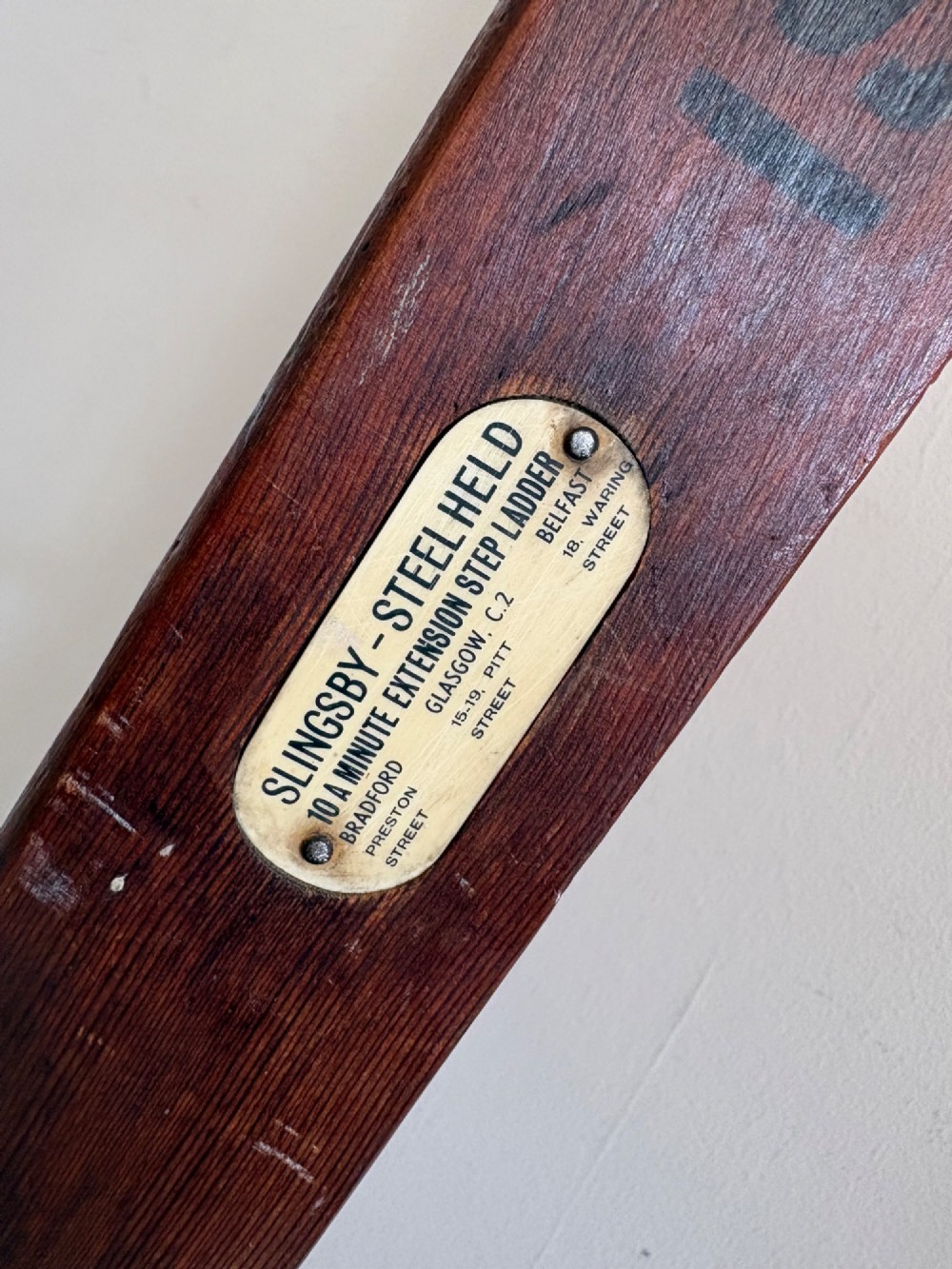 A tall early 20th-century pitch pine and elm library ladder with turned wooden rungs and a padded upper rail leaning against a white wall. View VIII