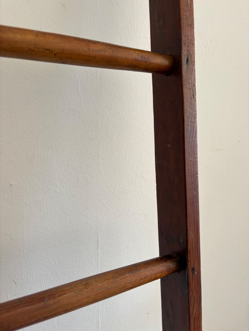 A tall early 20th-century pitch pine and elm library ladder with turned wooden rungs and a padded upper rail leaning against a white wall. View XII