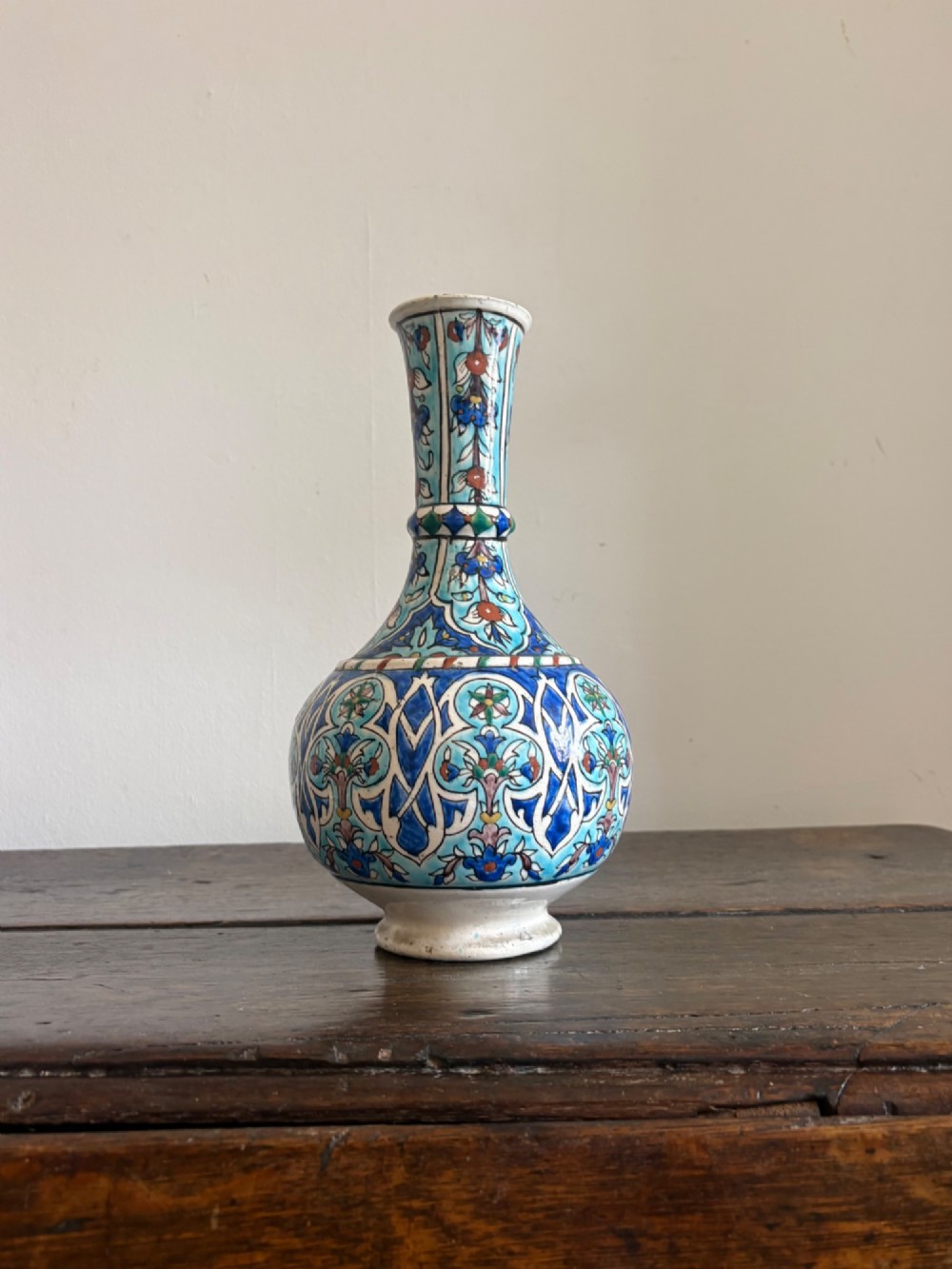 A hand-painted 19th-century Iznik style fritware bottle vase decorated with turquoise, cobalt blue, and red floral arabesque motifs. View II