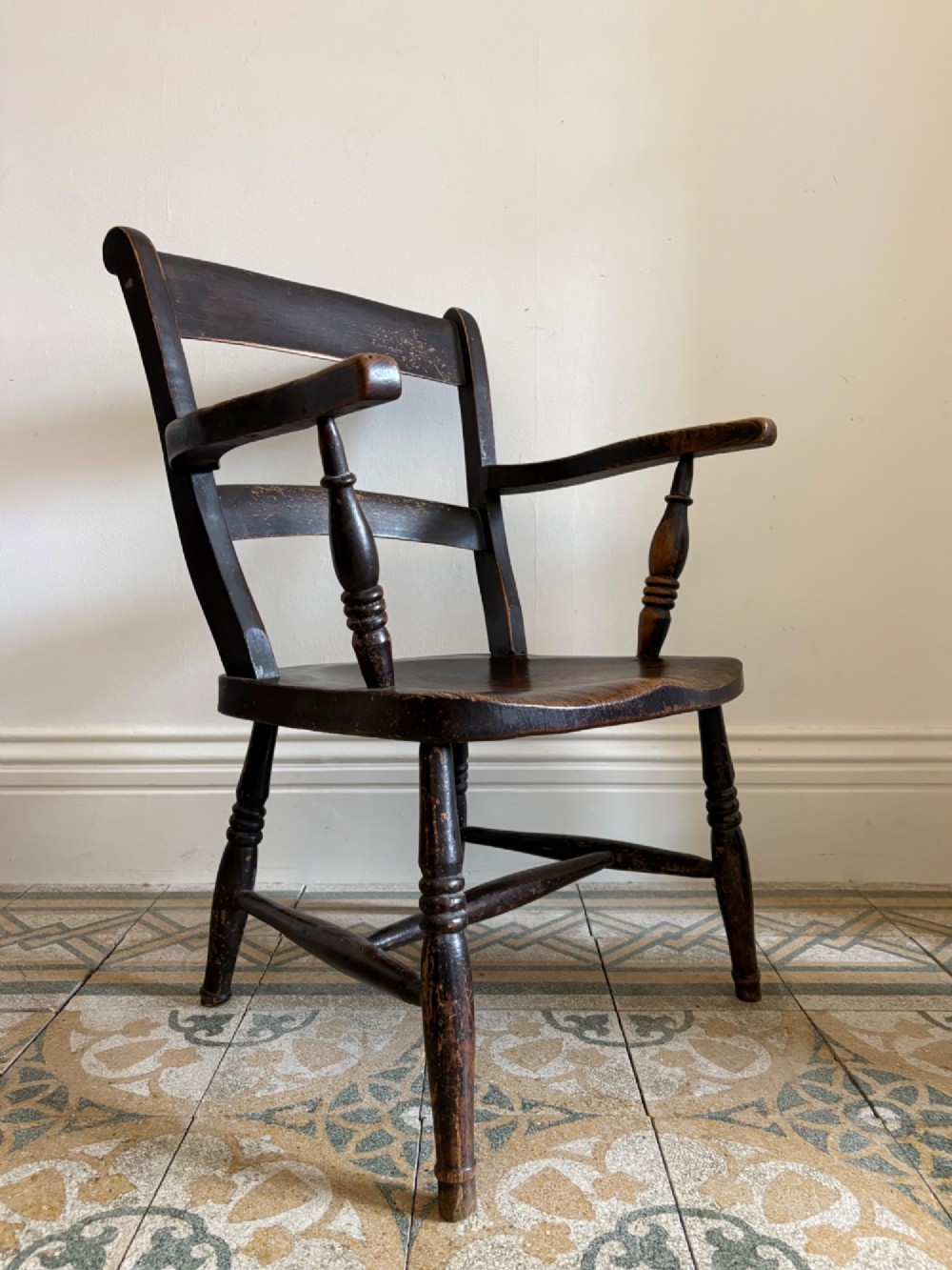 A mid-19th-century ebonised Thames Valley Windsor armchair with a slat back, shaped elm seat, and turned wooden legs.