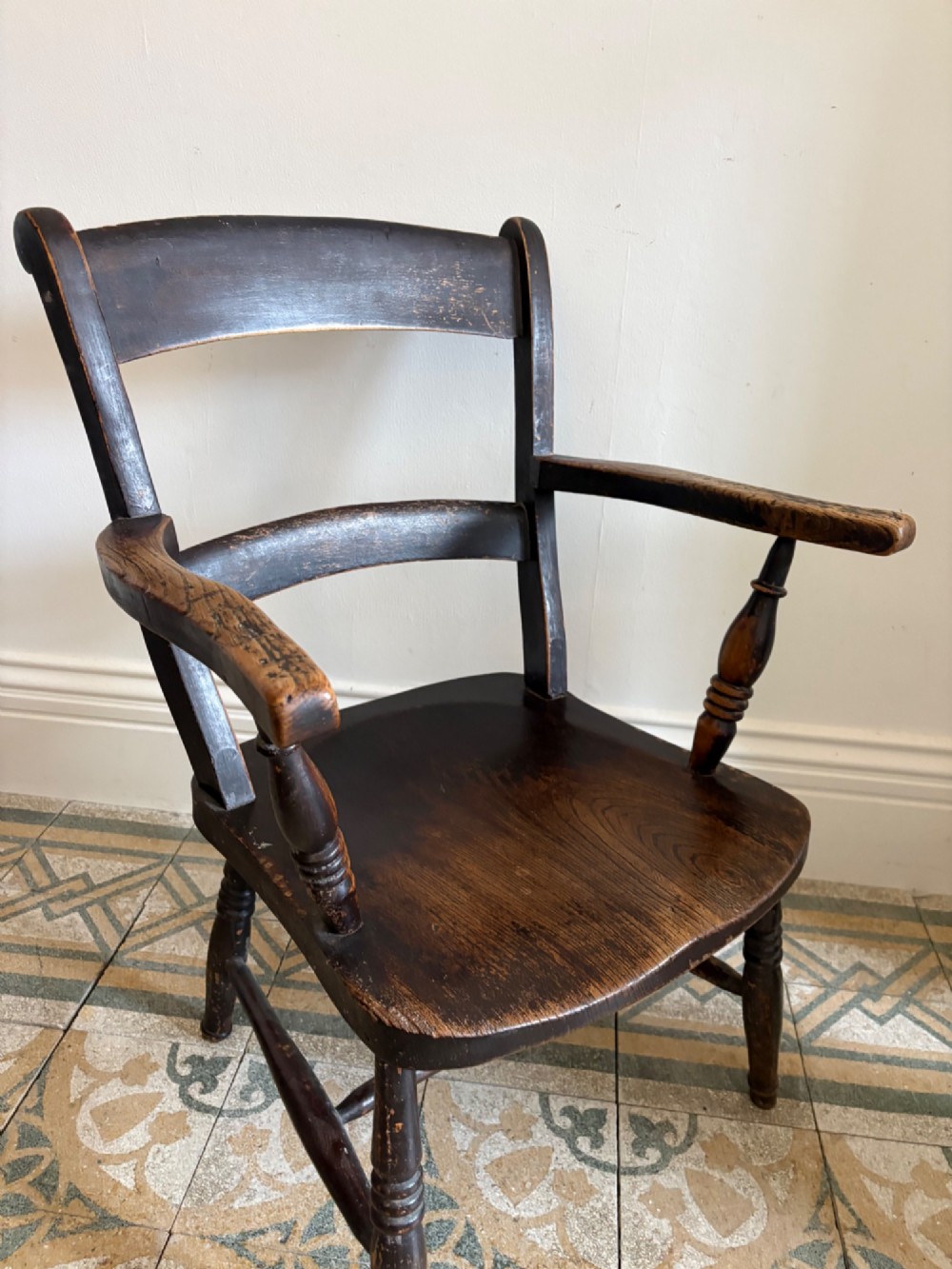 A mid-19th-century ebonised Thames Valley Windsor armchair with a slat back, shaped elm seat, and turned wooden legs. View V