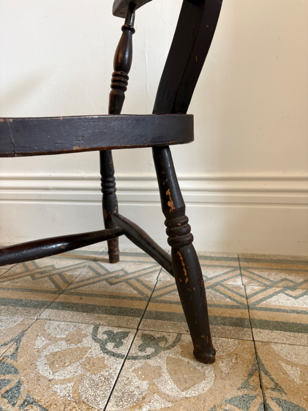 A mid-19th-century ebonised Thames Valley Windsor armchair with a slat back, shaped elm seat, and turned wooden legs. View VII