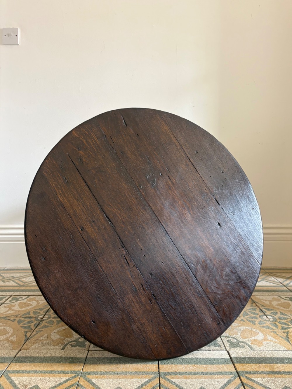 A nineteenth-century round wooden cricket table featuring a circular oak plank top resting on three dark pine legs. View III