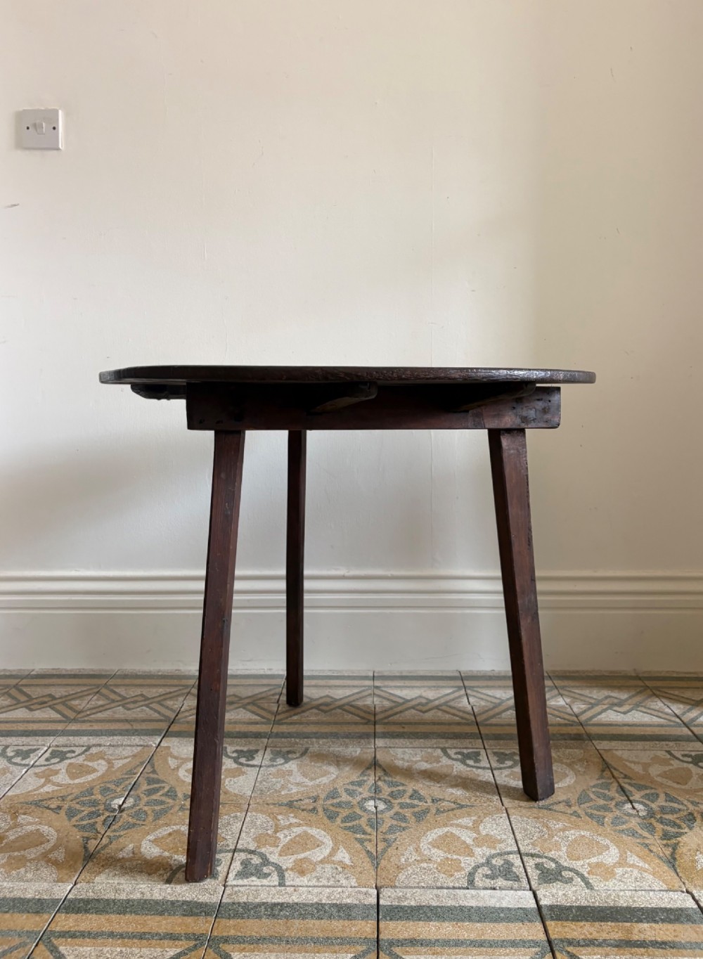 A nineteenth-century round wooden cricket table featuring a circular oak plank top resting on three dark pine legs. View IV
