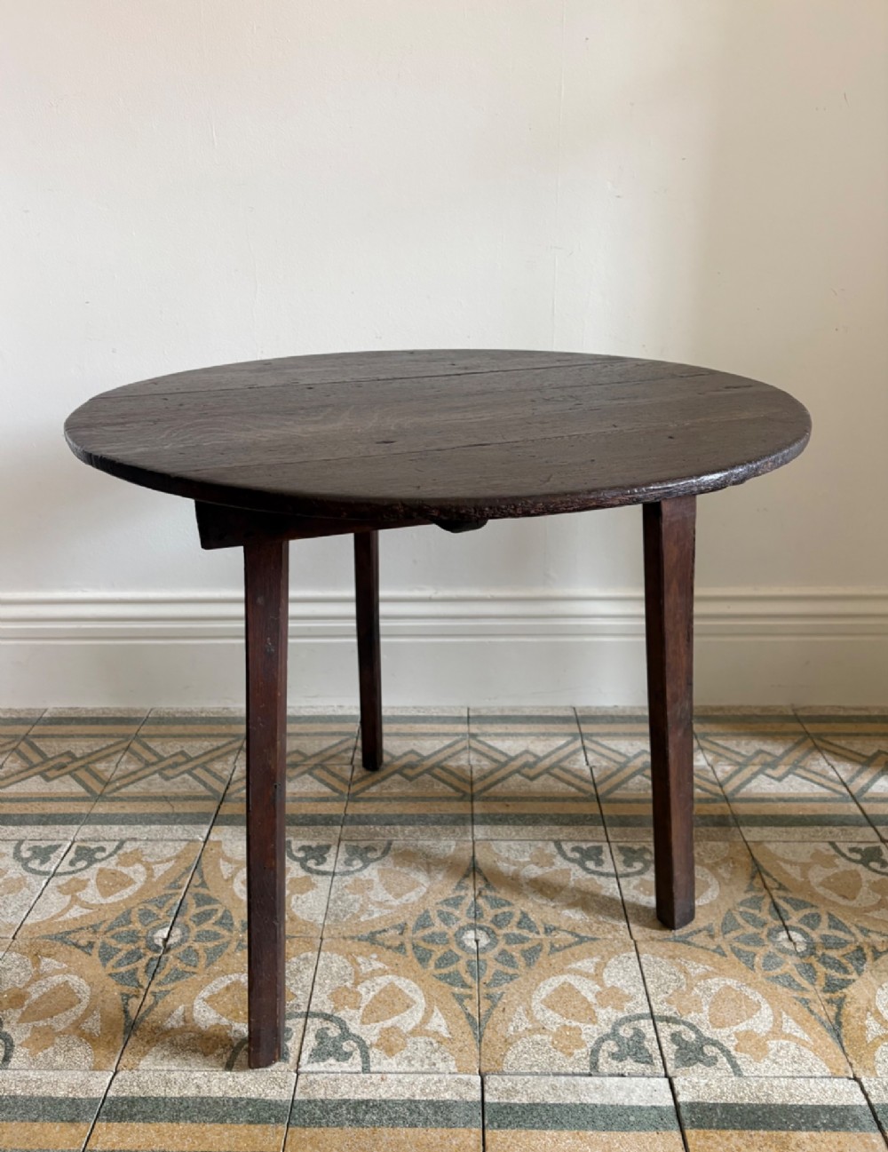 A nineteenth-century round wooden cricket table featuring a circular oak plank top resting on three dark pine legs. View V