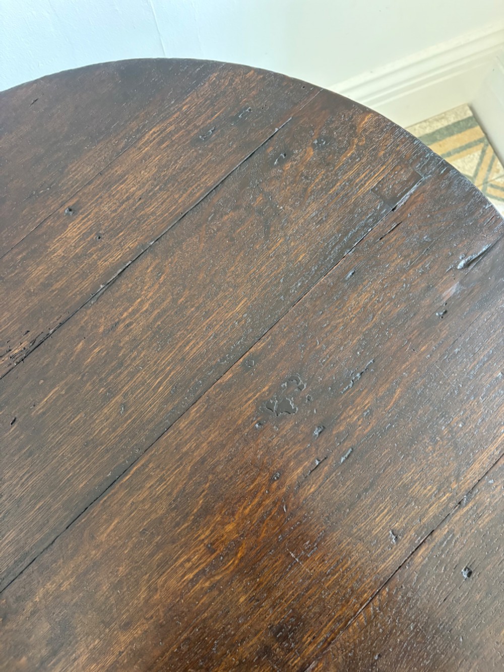 A nineteenth-century round wooden cricket table featuring a circular oak plank top resting on three dark pine legs. View VI