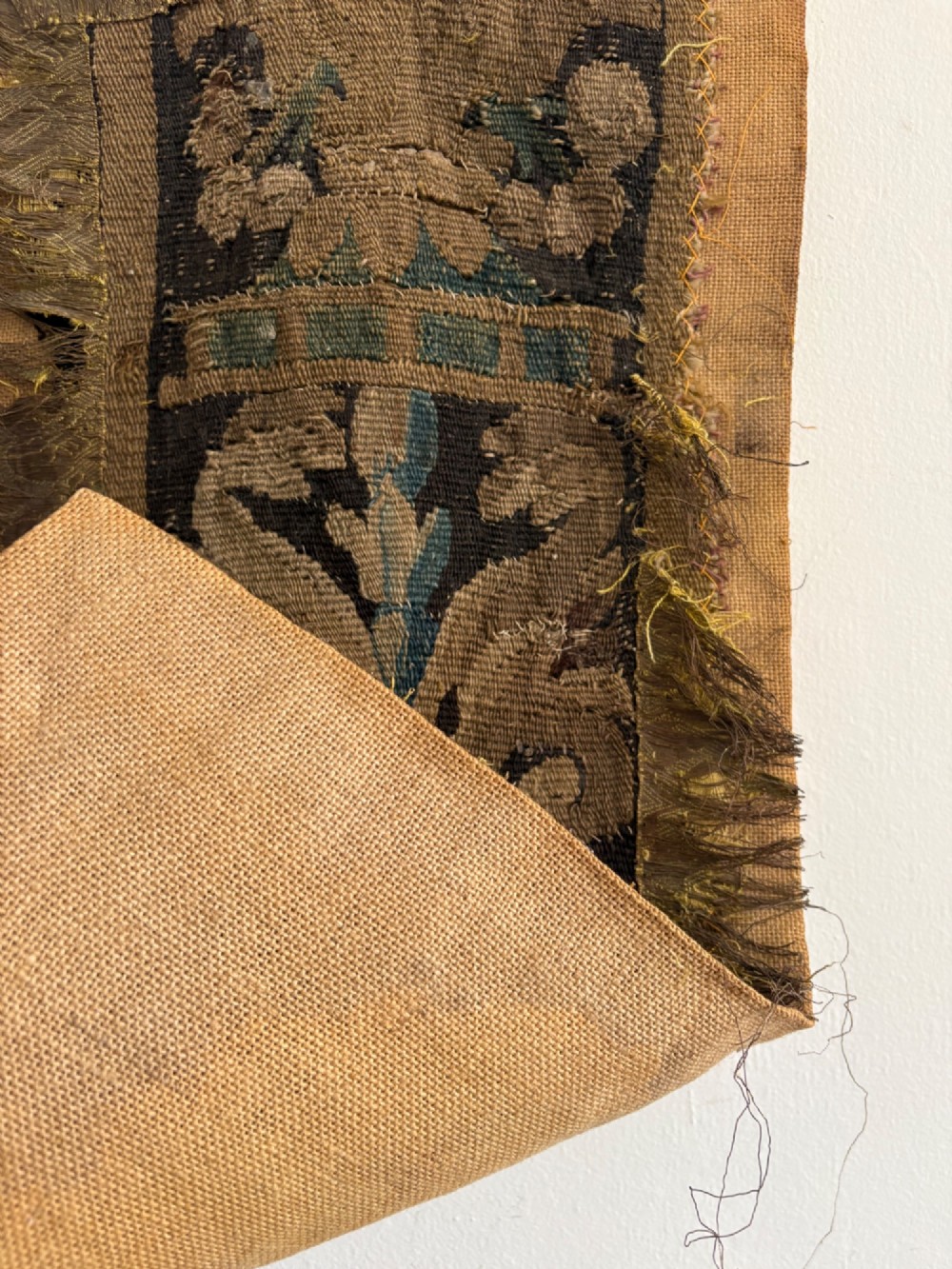 A vertical fragment of an antique hand-woven verdure tapestry featuring acanthus leaf motifs, mounted onto a natural linen backing. View IV