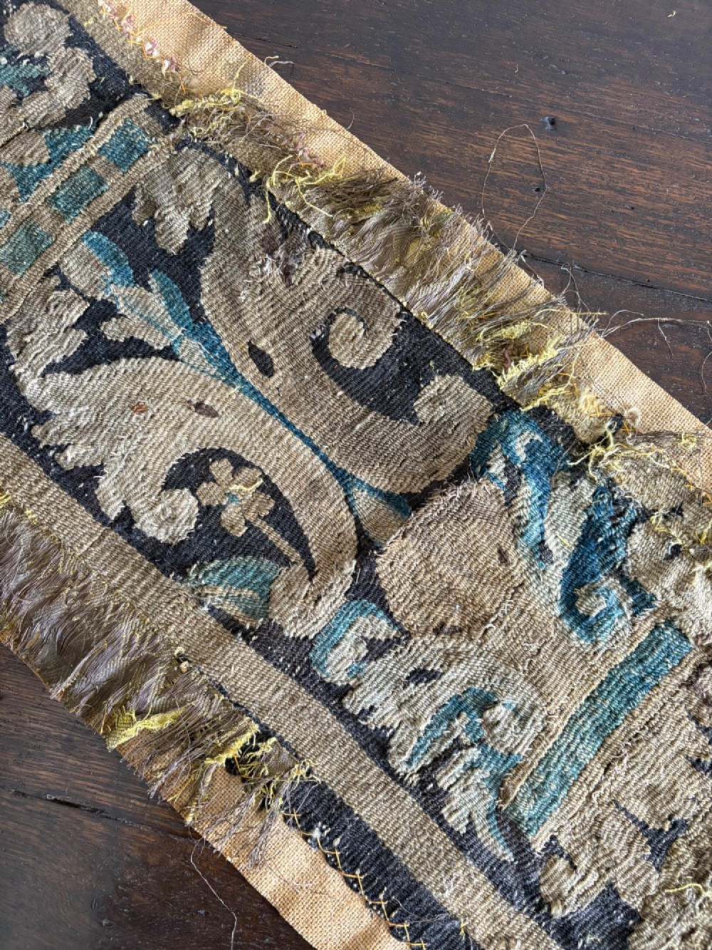 A vertical fragment of an antique hand-woven verdure tapestry featuring acanthus leaf motifs, mounted onto a natural linen backing. View IX