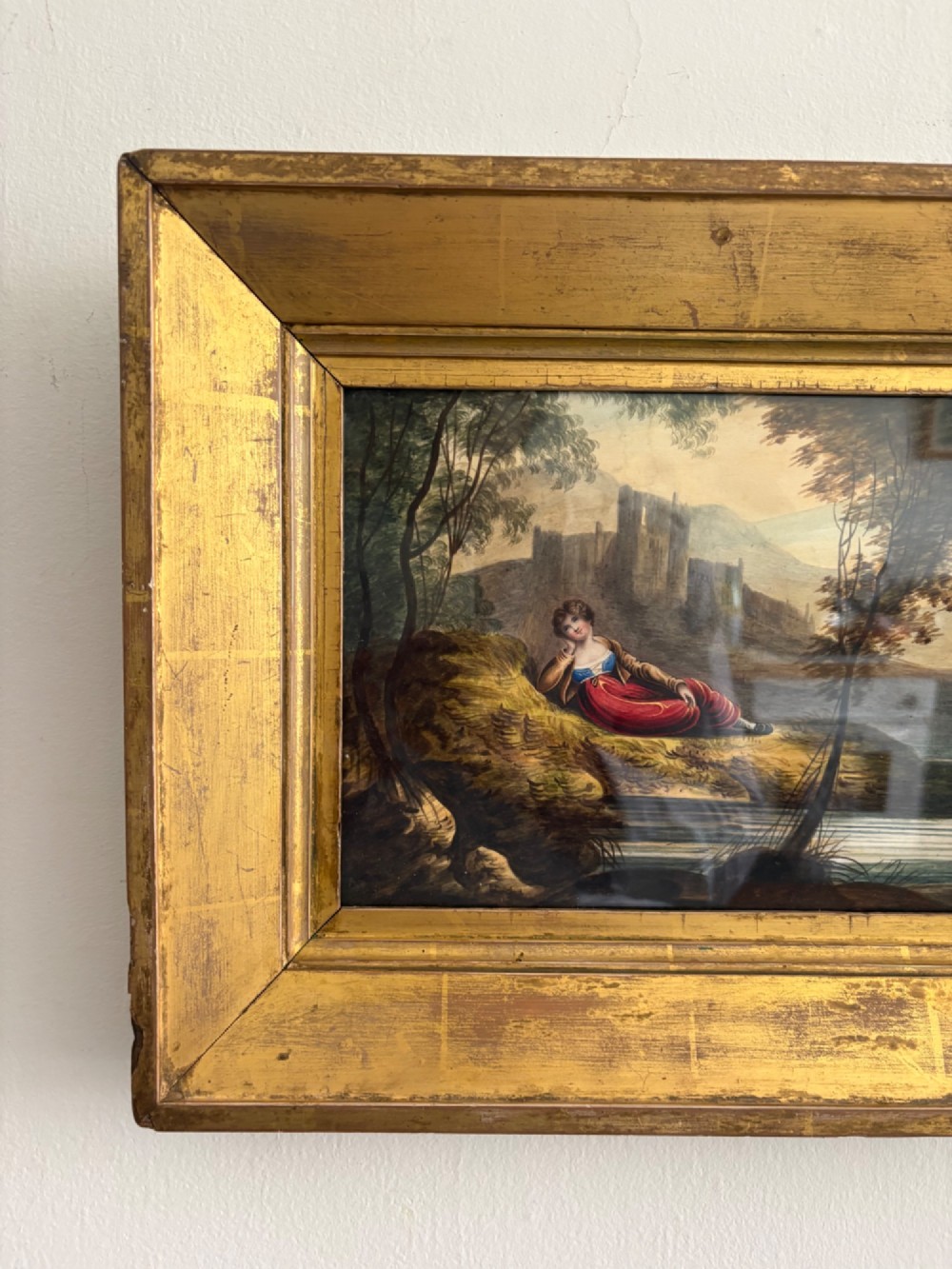 A 19th-century watercolour painting depicting a reclining figure in a landscape with ruins, set inside a broad giltwood frame. View III