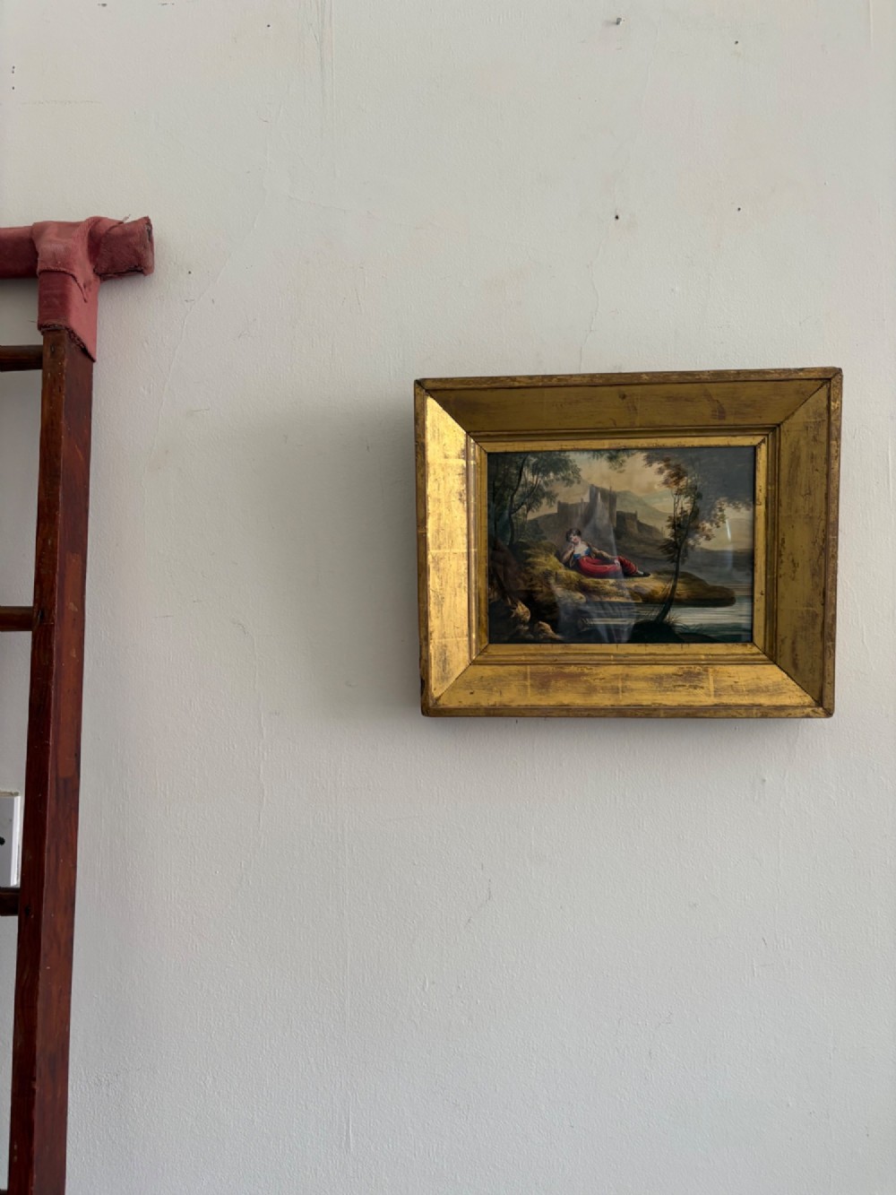 A 19th-century watercolour painting depicting a reclining figure in a landscape with ruins, set inside a broad giltwood frame. View VI