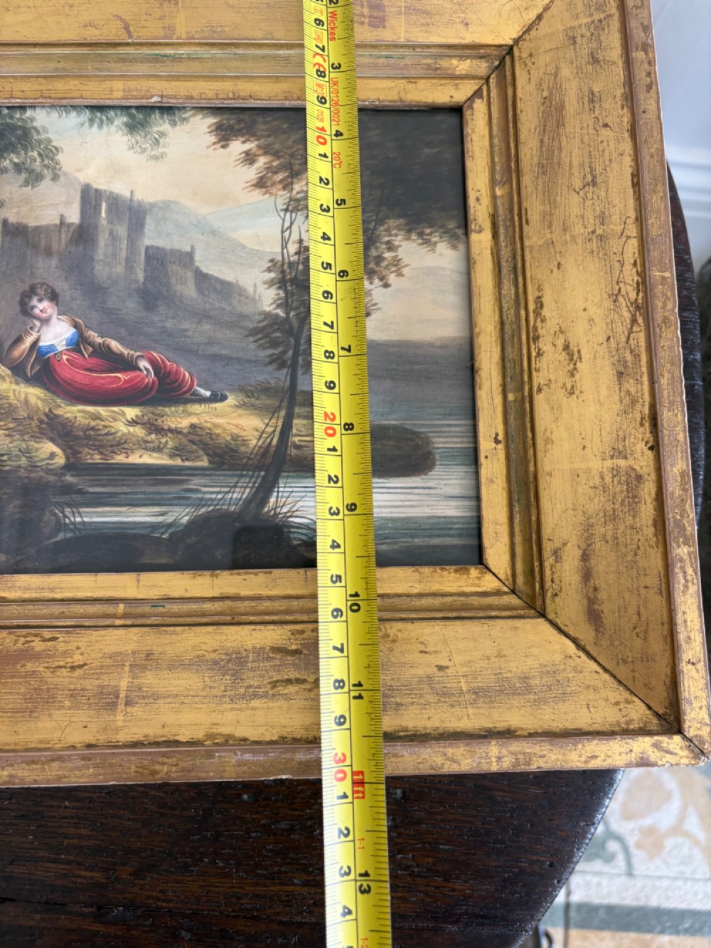 A 19th-century watercolour painting depicting a reclining figure in a landscape with ruins, set inside a broad giltwood frame. View XII