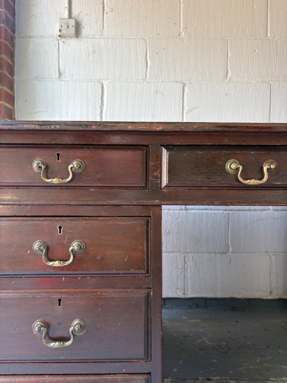 An antique dark mahogany pedestal desk featuring a green leather inset writing top, nine drawers with brass swan-neck handles, and twin pedestals on plinth bases. View VIII