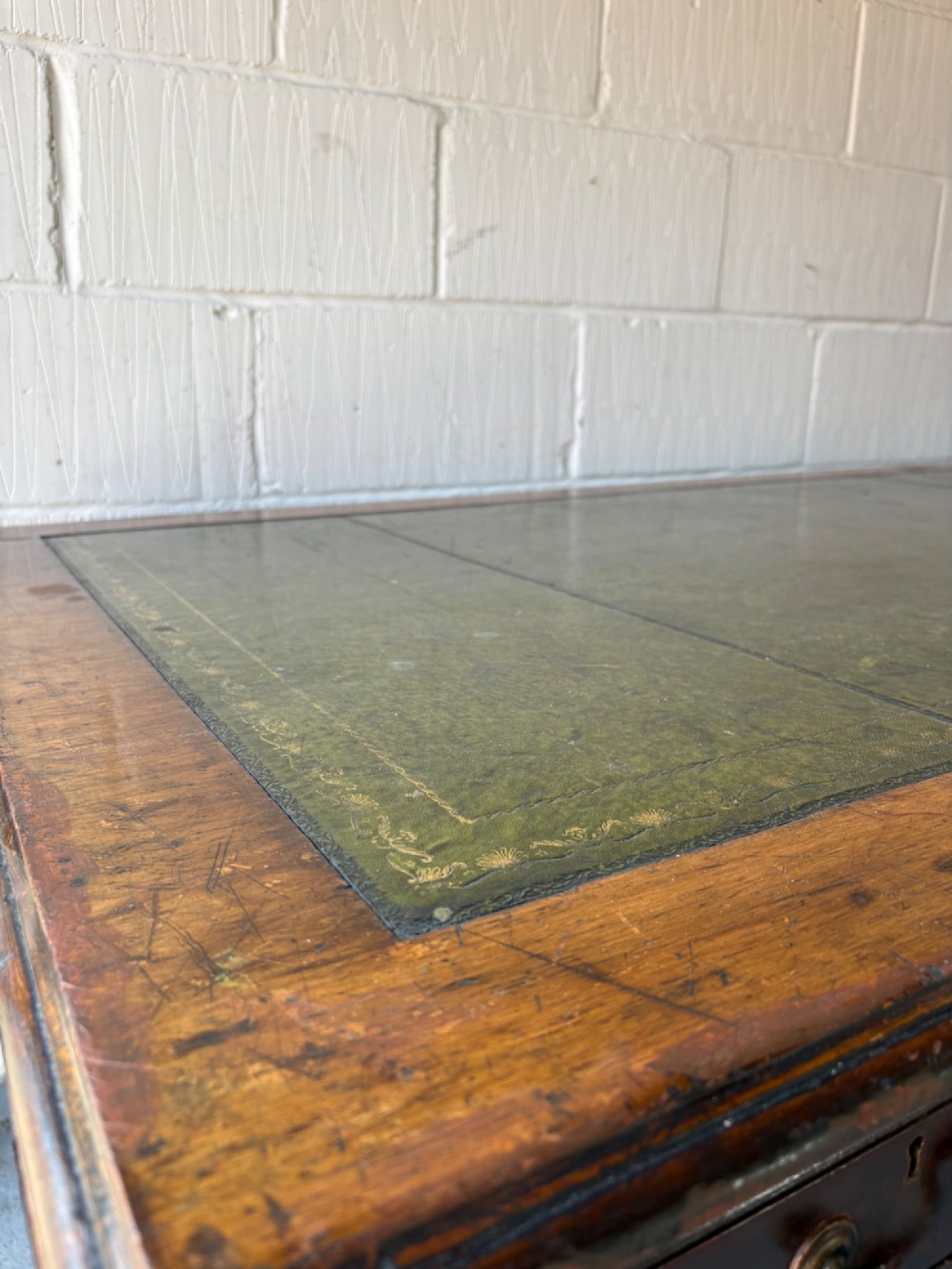 An antique dark mahogany pedestal desk featuring a green leather inset writing top, nine drawers with brass swan-neck handles, and twin pedestals on plinth bases. View IX