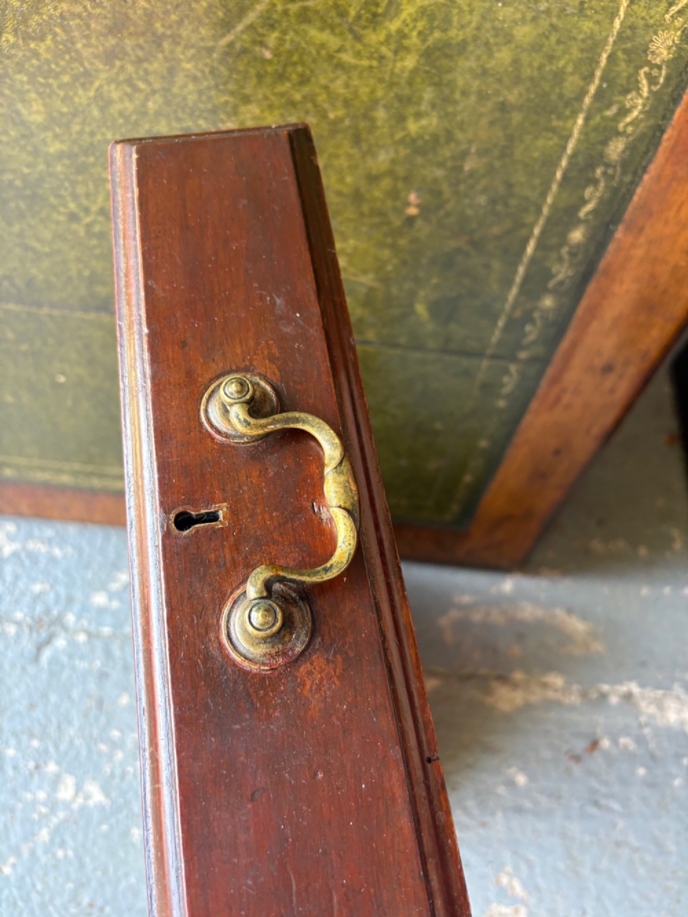 An antique dark mahogany pedestal desk featuring a green leather inset writing top, nine drawers with brass swan-neck handles, and twin pedestals on plinth bases. View XI