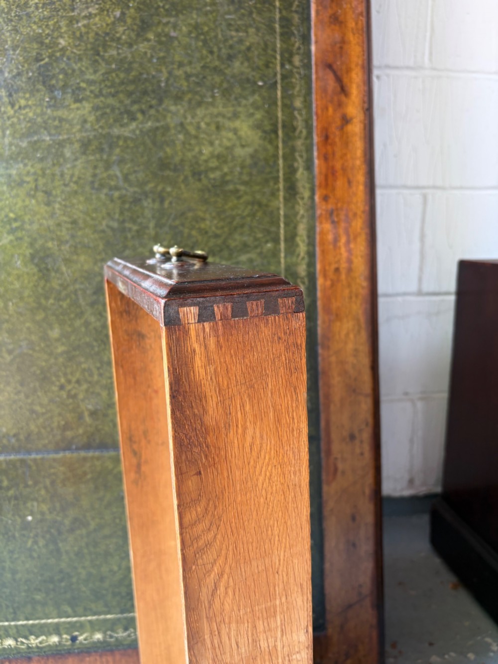 An antique dark mahogany pedestal desk featuring a green leather inset writing top, nine drawers with brass swan-neck handles, and twin pedestals on plinth bases. View XV