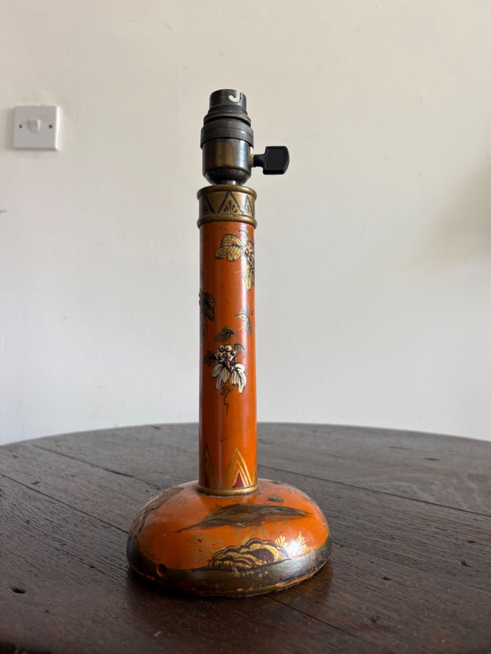 A mandarin orange lacquered table lamp base decorated with gold hand-painted floral motifs and fitted with a brass bulb holder.