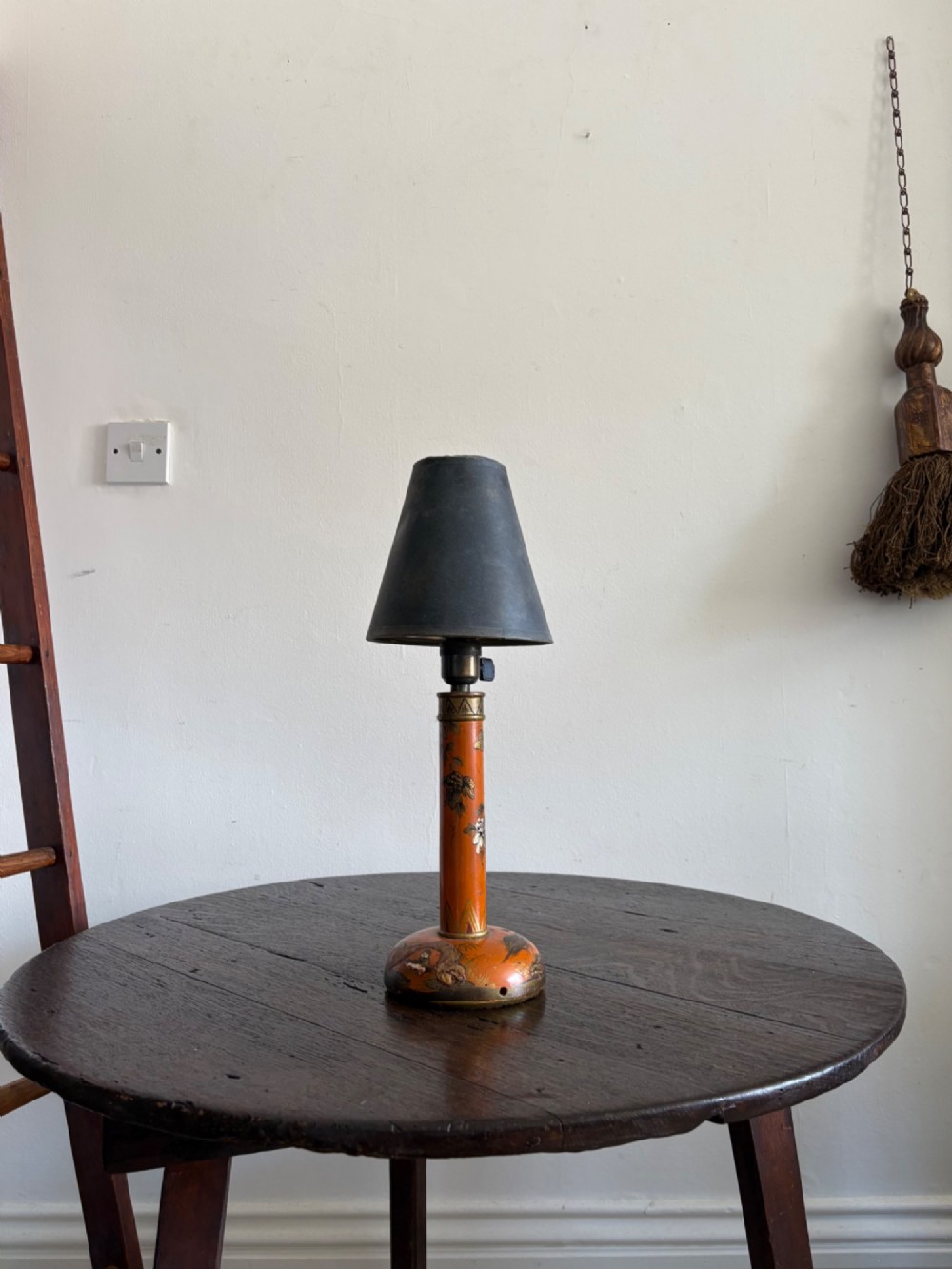 A mandarin orange lacquered table lamp base decorated with gold hand-painted floral motifs and fitted with a brass bulb holder. View X