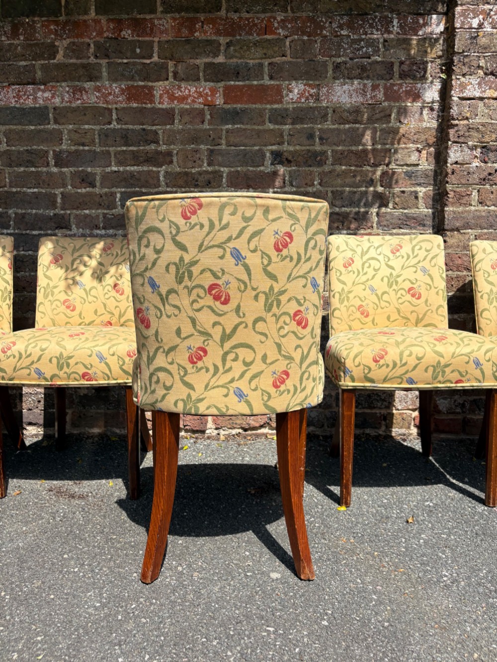 A row of 1930s Art Deco dining chairs featuring yellow floral pattern upholstery and dark oak tapered legs. View IV