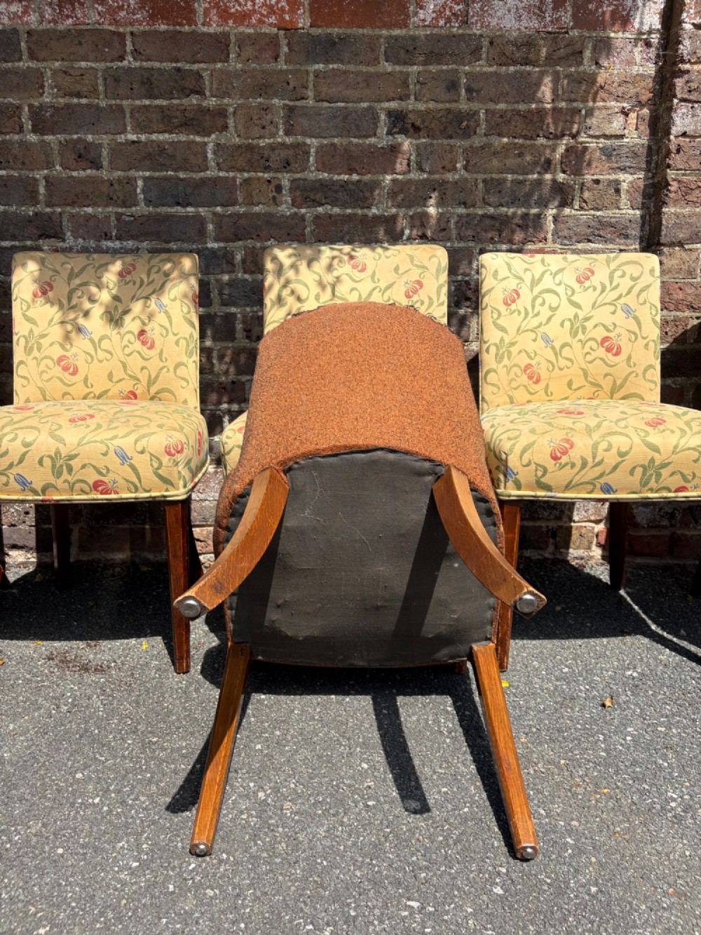 A row of 1930s Art Deco dining chairs featuring yellow floral pattern upholstery and dark oak tapered legs. View VI