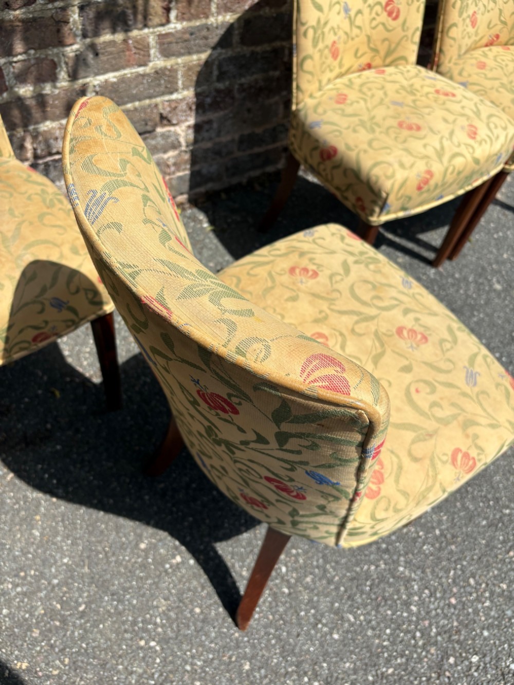 A row of 1930s Art Deco dining chairs featuring yellow floral pattern upholstery and dark oak tapered legs. View VII