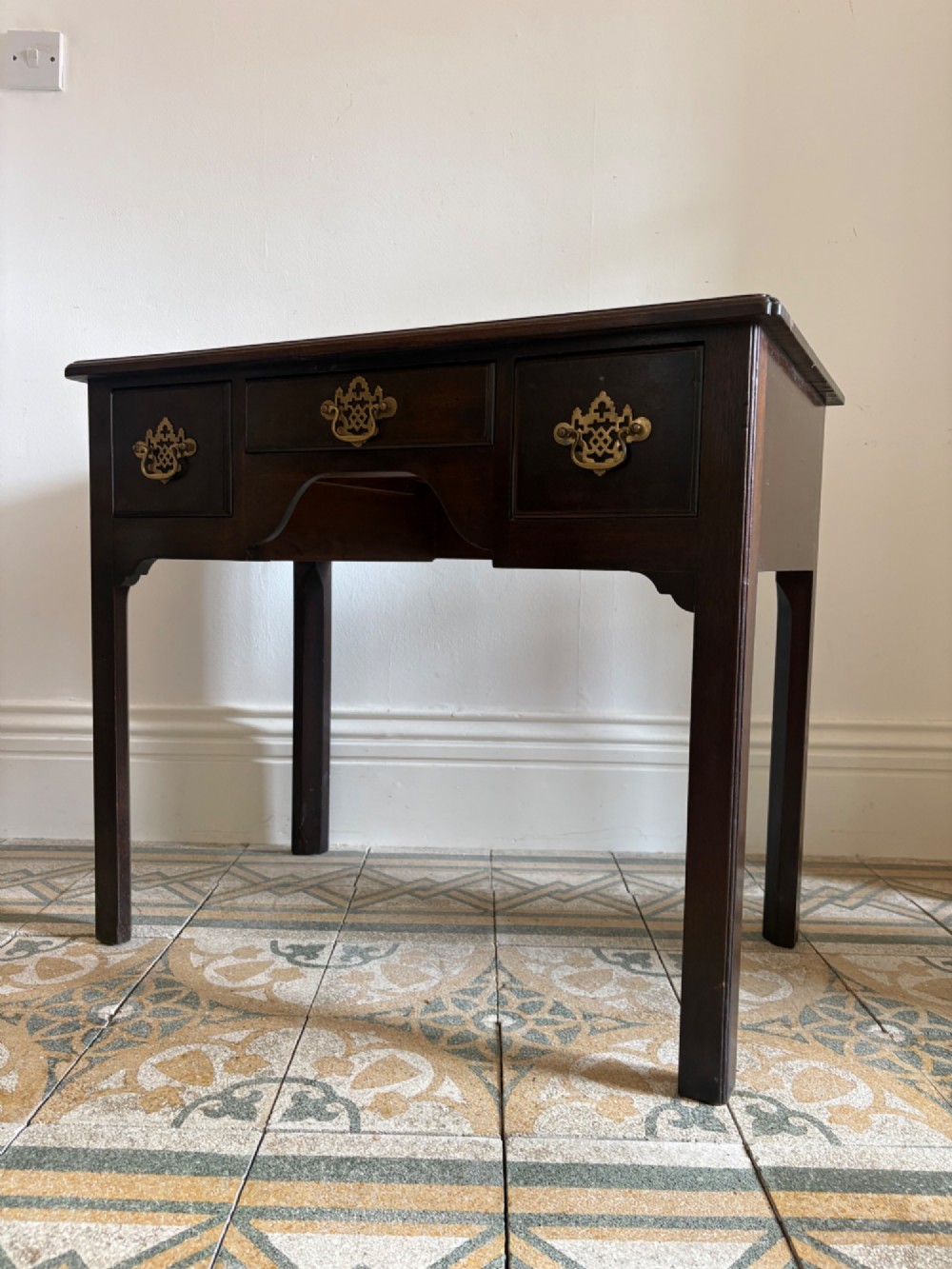 A George III style mahogany lowboy table featuring three drawers with decorative brass handles and an arched apron. View III
