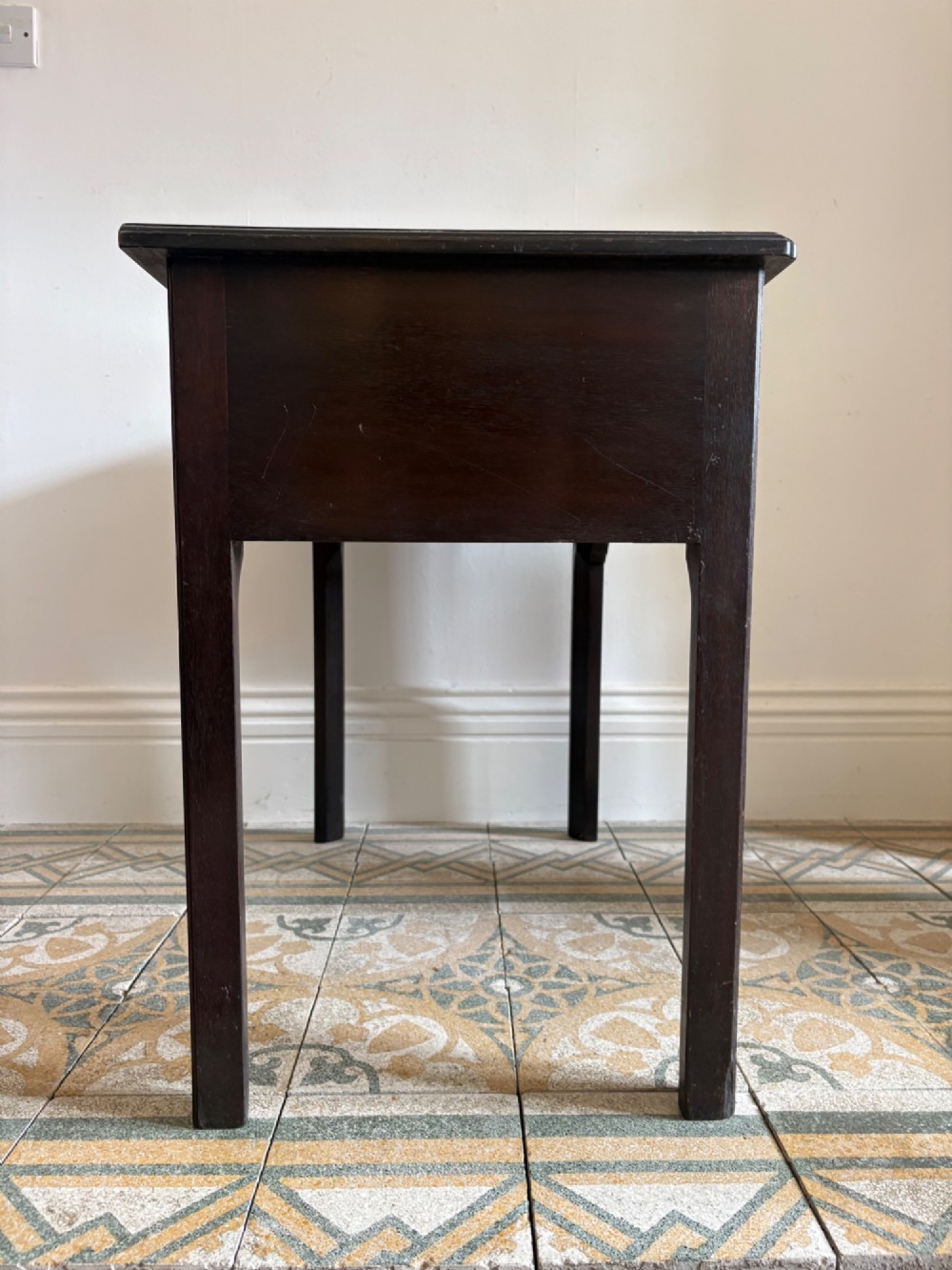 A George III style mahogany lowboy table featuring three drawers with decorative brass handles and an arched apron. View IV