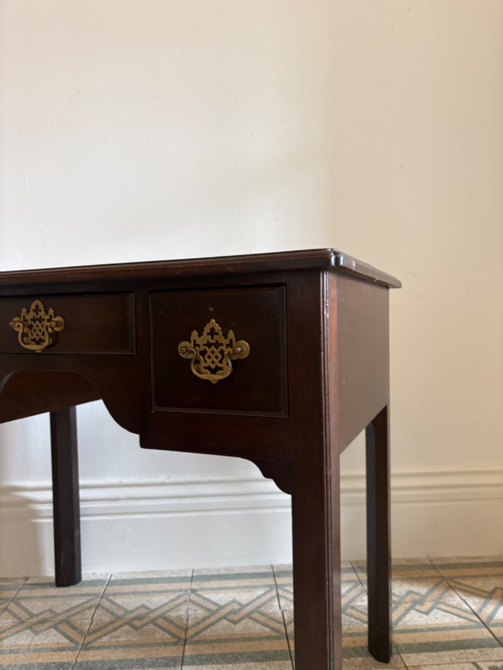 A George III style mahogany lowboy table featuring three drawers with decorative brass handles and an arched apron. View V