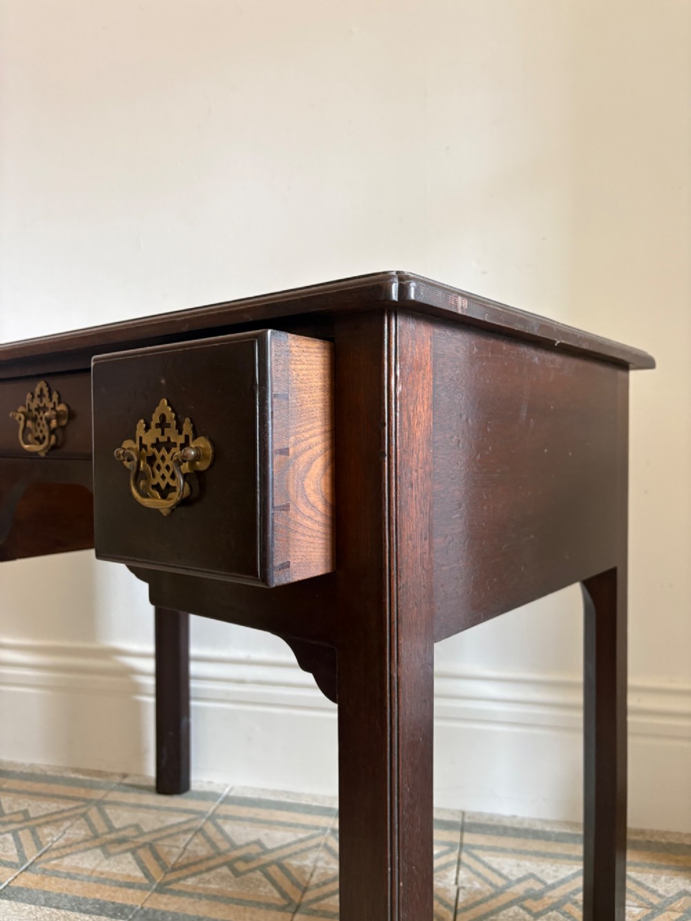 A George III style mahogany lowboy table featuring three drawers with decorative brass handles and an arched apron. View VI