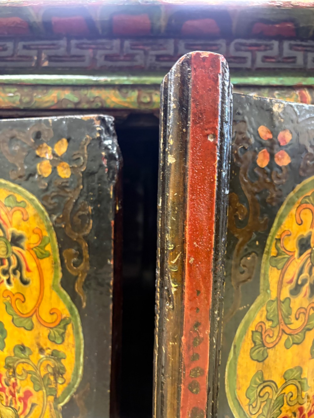 A 19th-century Tibetan wooden cabinet featuring four central hand-painted floral panels framed in red and gold mineral pigments. View VII