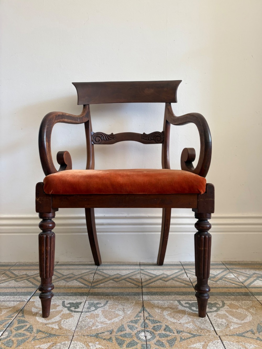 Profile view of a Late Regency mahogany open armchair with scrolled armrests, reeded front legs, and a rust orange velvet drop-in seat. View II