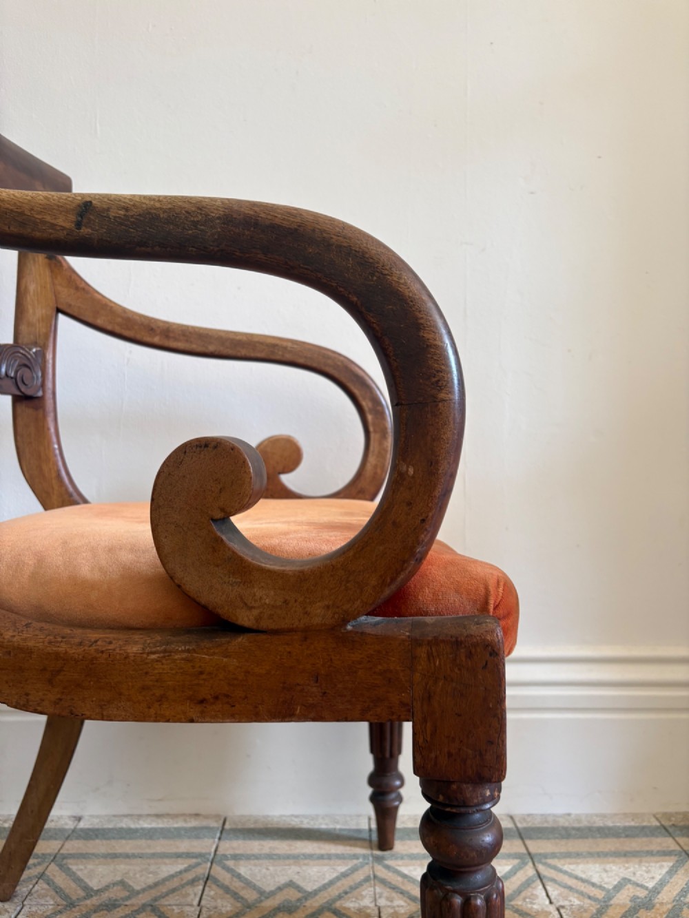 Profile view of a Late Regency mahogany open armchair with scrolled armrests, reeded front legs, and a rust orange velvet drop-in seat. View III