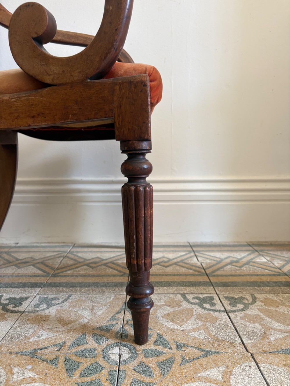 Profile view of a Late Regency mahogany open armchair with scrolled armrests, reeded front legs, and a rust orange velvet drop-in seat. View IV