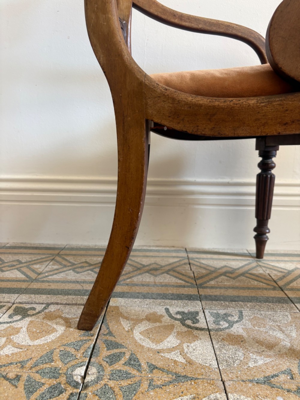 Profile view of a Late Regency mahogany open armchair with scrolled armrests, reeded front legs, and a rust orange velvet drop-in seat. View V