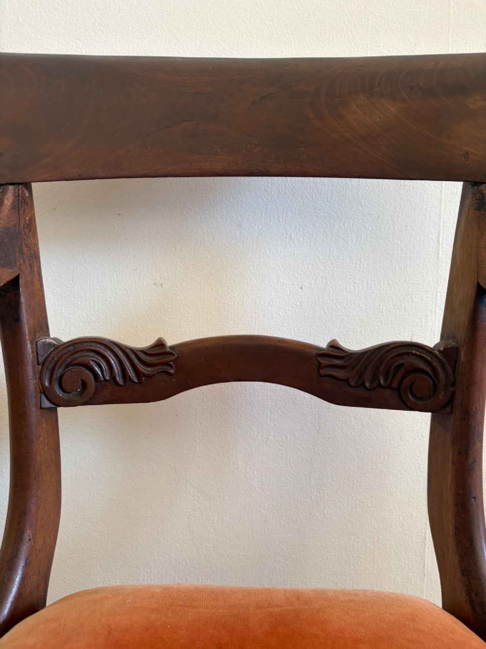 Profile view of a Late Regency mahogany open armchair with scrolled armrests, reeded front legs, and a rust orange velvet drop-in seat. View VI