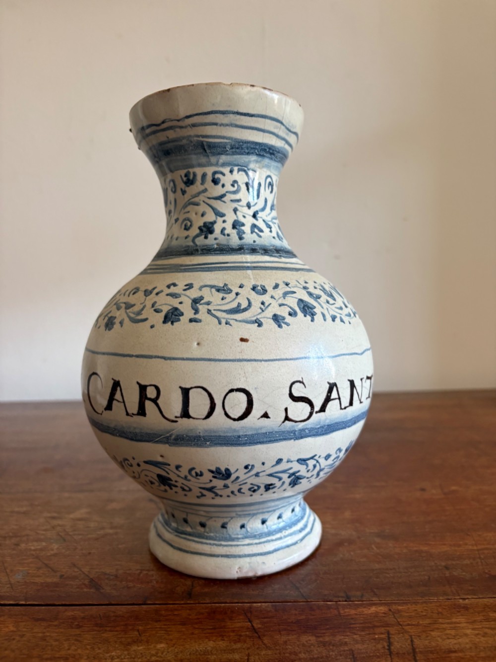 An 18th to 19th century Italian blue and white tin-glazed earthenware apothecary jar featuring painted foliate borders and the Latin inscription CARDO SANT.