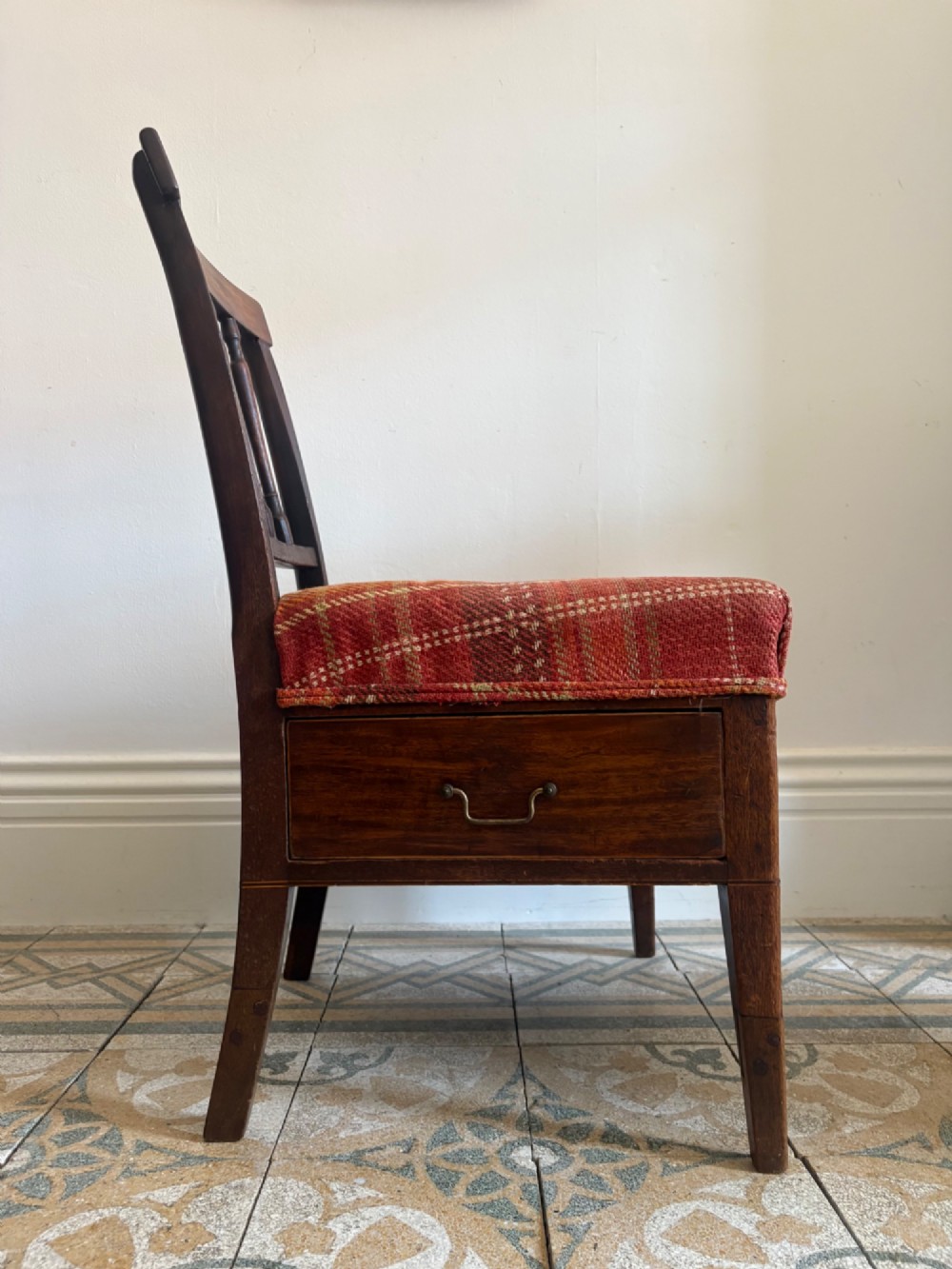 A Regency mahogany and beech side chair featuring a red plaid upholstered seat above an integrated wooden drawer with a brass drop handle.