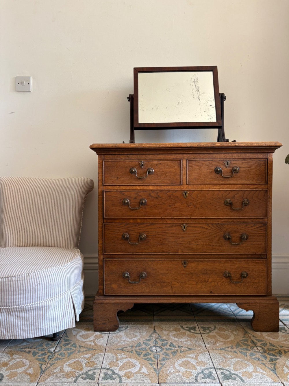 A George III style medium oak chest of drawers featuring two short drawers above three long drawers, resting on shaped bracket feet with brass handles. View III