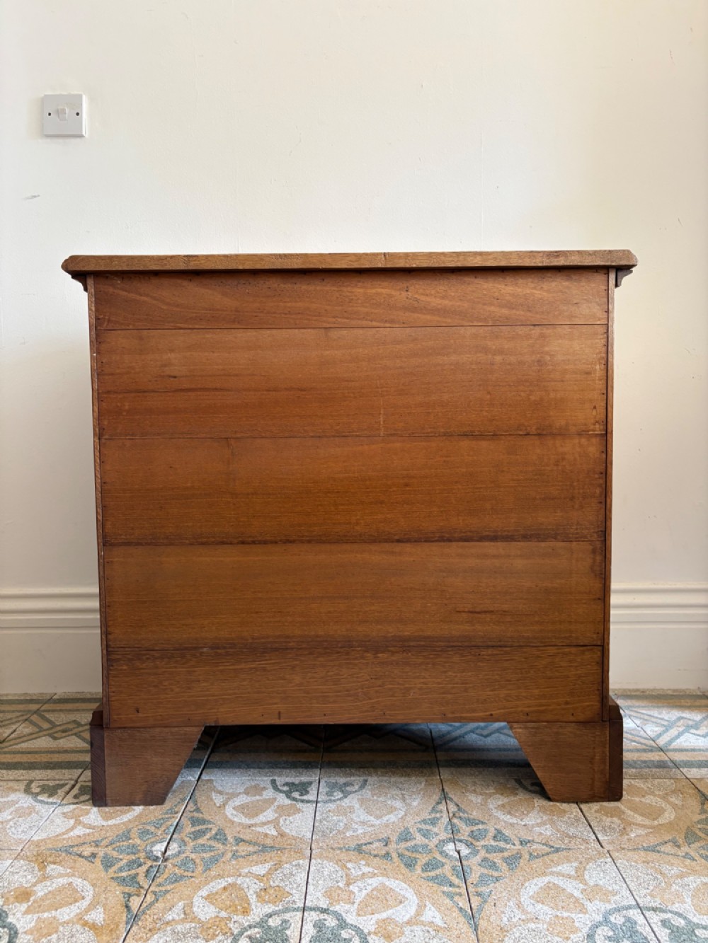 A George III style medium oak chest of drawers featuring two short drawers above three long drawers, resting on shaped bracket feet with brass handles. View VI