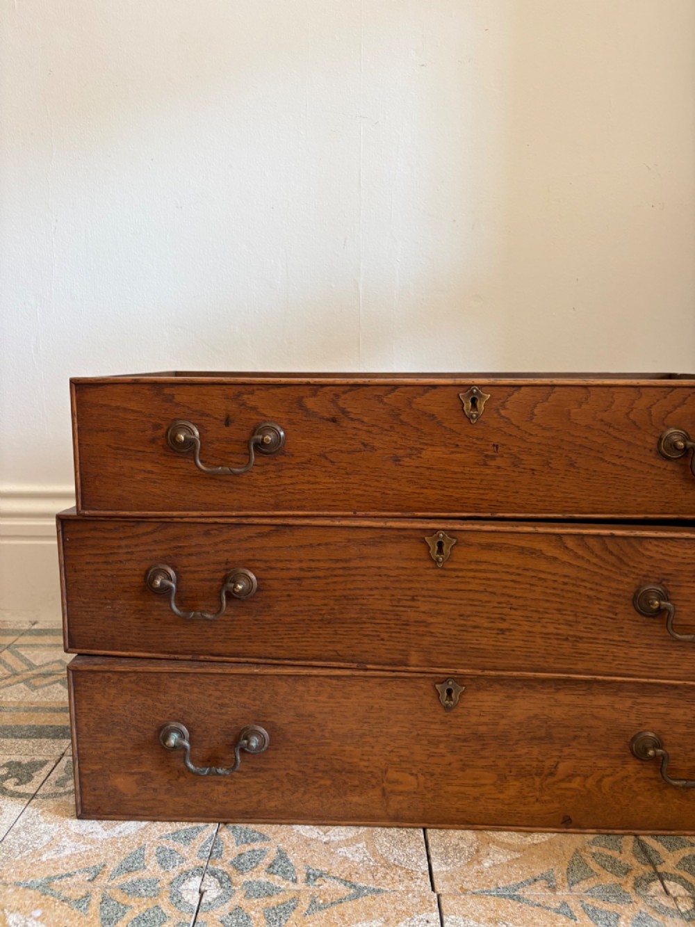 A George III style medium oak chest of drawers featuring two short drawers above three long drawers, resting on shaped bracket feet with brass handles. View VII