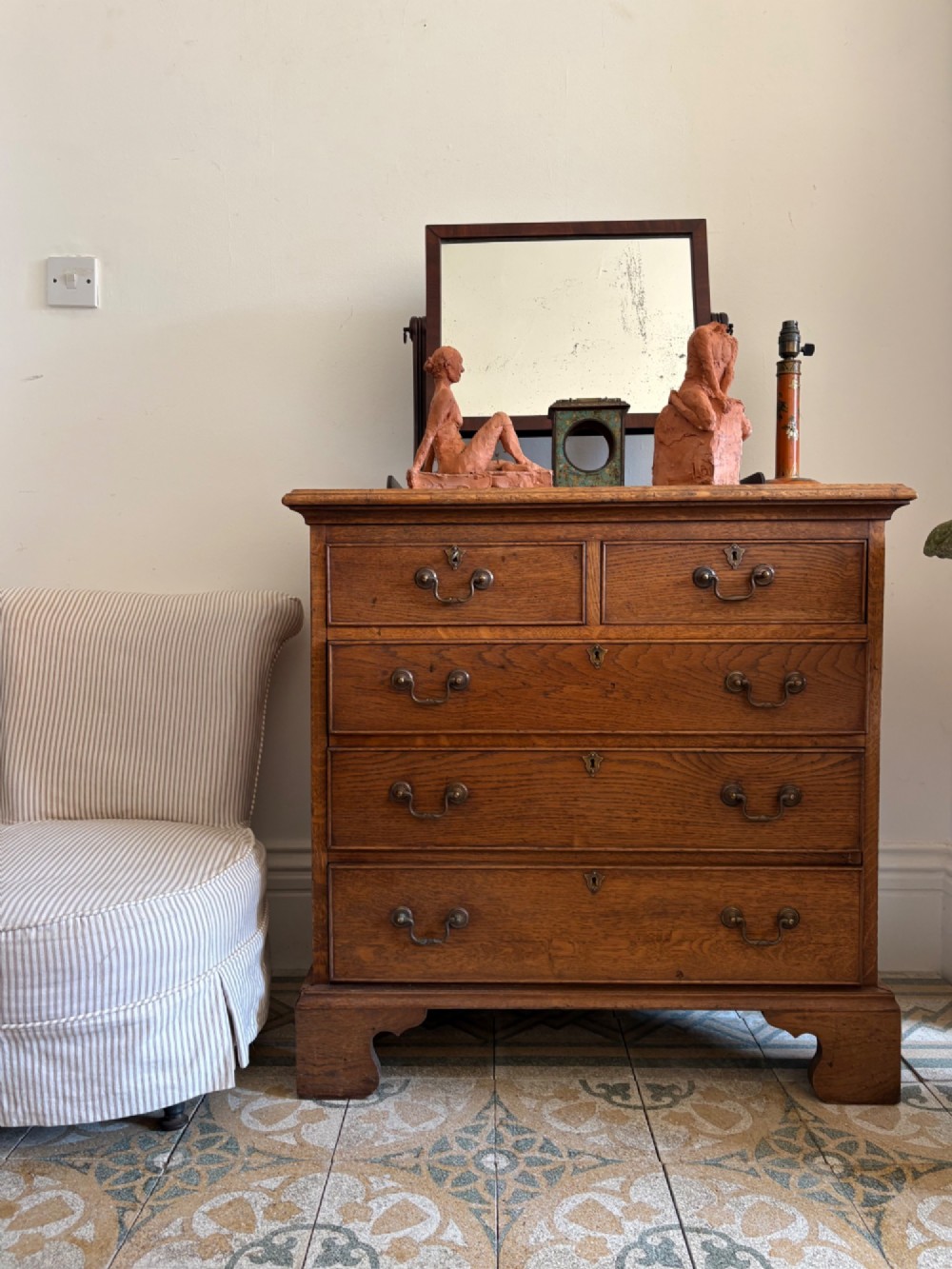 A George III style medium oak chest of drawers featuring two short drawers above three long drawers, resting on shaped bracket feet with brass handles. View X