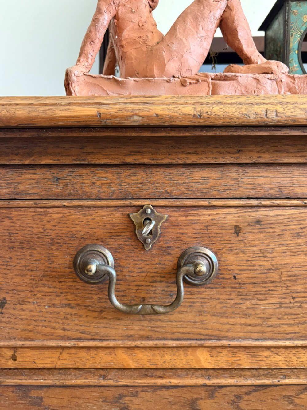 A George III style medium oak chest of drawers featuring two short drawers above three long drawers, resting on shaped bracket feet with brass handles. View XI