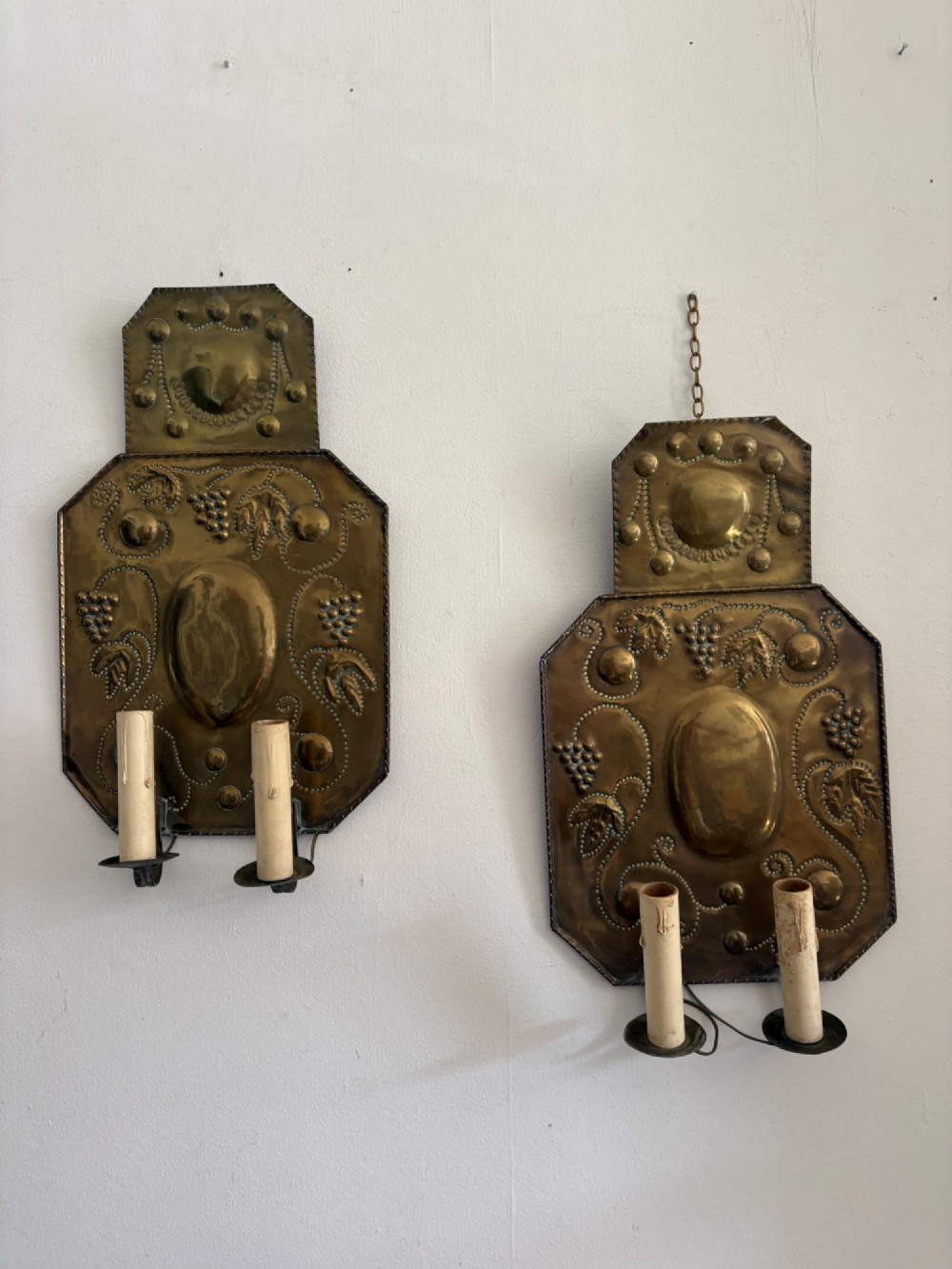Pair of late 19th-century Dutch repousse brass two-branch wall sconces decorated with embossed grape vine motifs and oval central bosses.