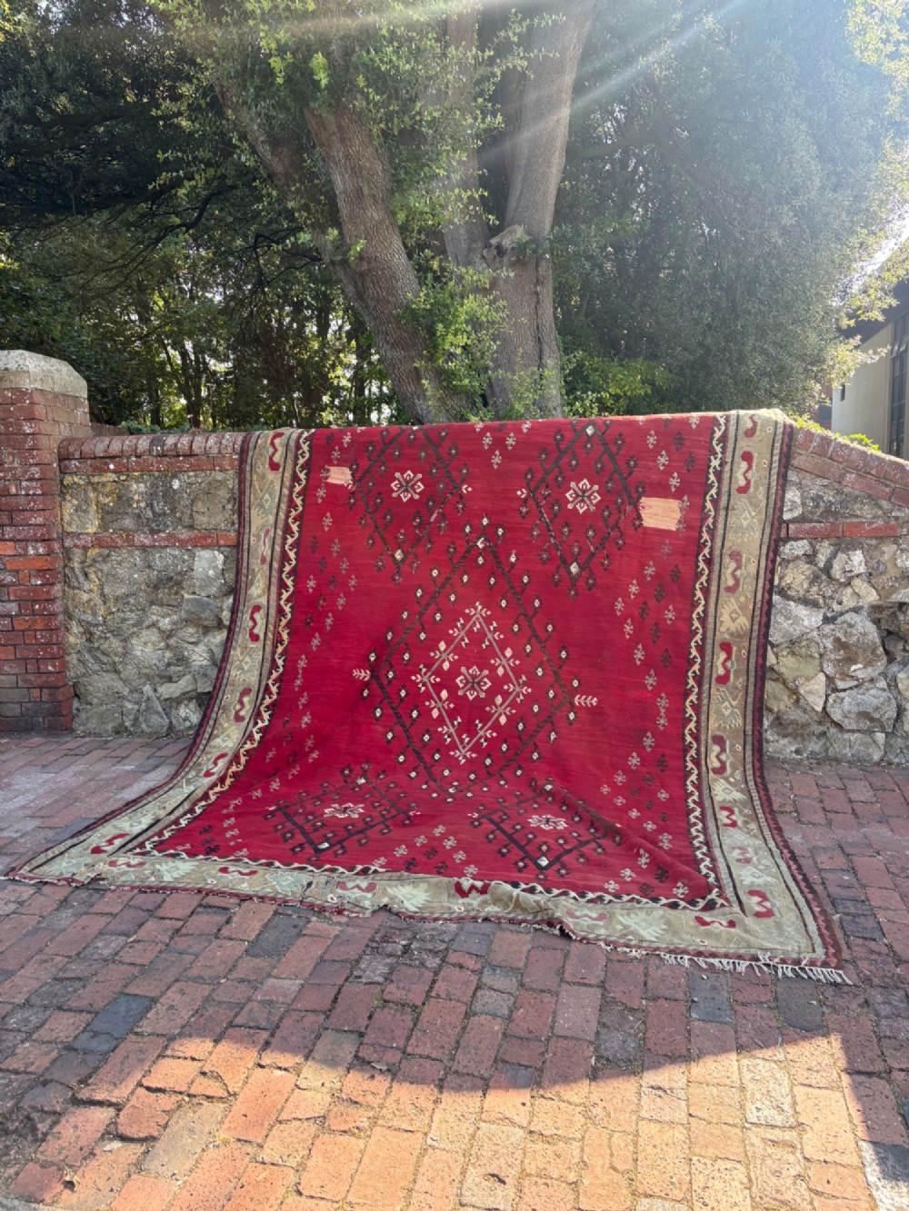 A large handwoven Anatolian flatweave kilim rug featuring a vivid red field patterned with dark geometric diamond motifs and framed by a light beige border. View II