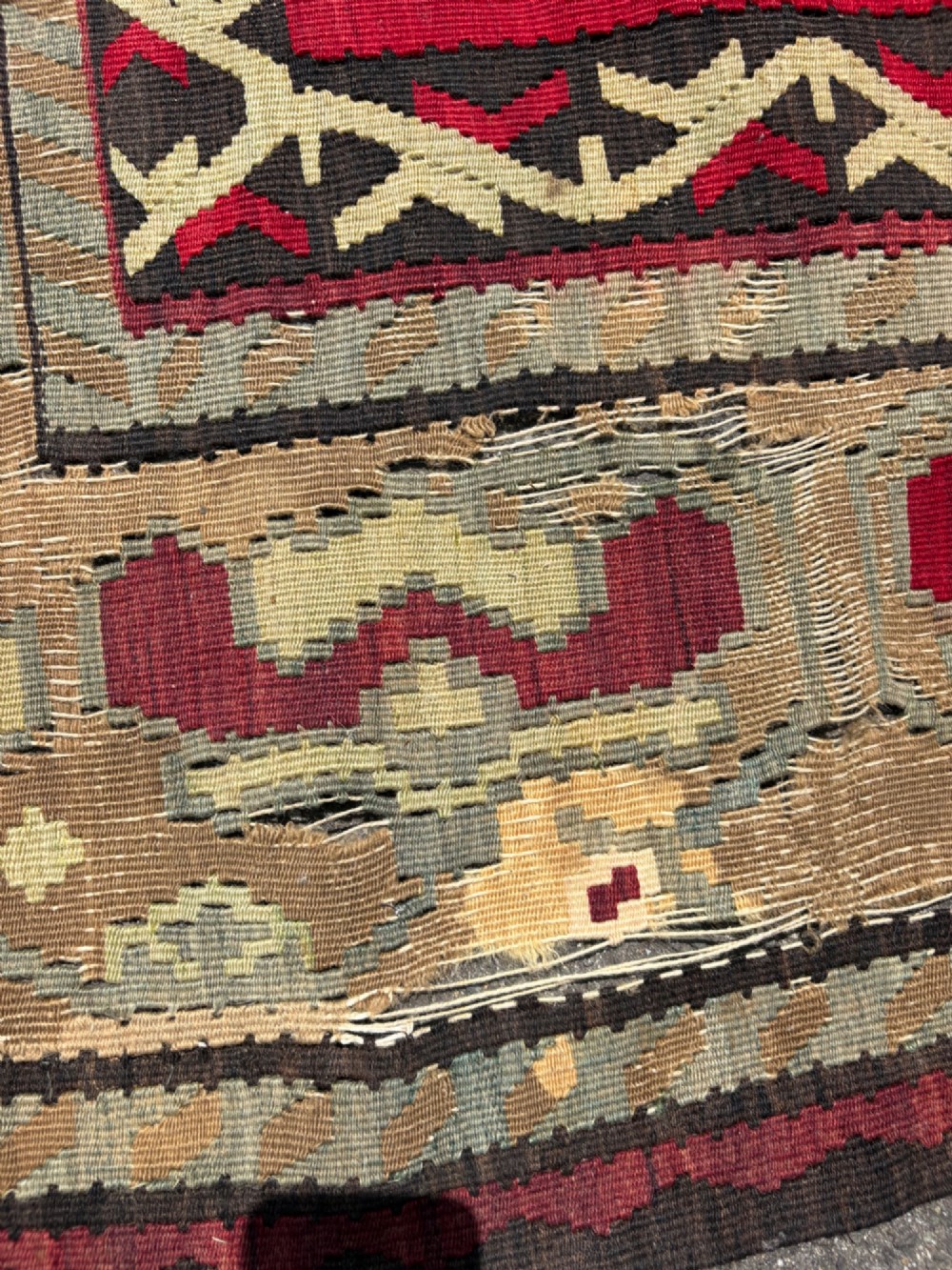 A large handwoven Anatolian flatweave kilim rug featuring a vivid red field patterned with dark geometric diamond motifs and framed by a light beige border. View VI