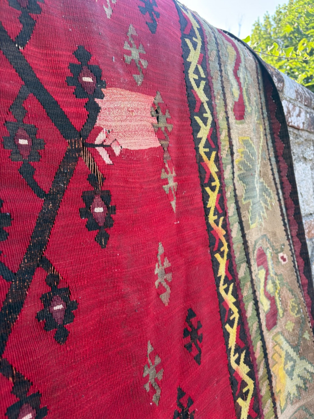 A large handwoven Anatolian flatweave kilim rug featuring a vivid red field patterned with dark geometric diamond motifs and framed by a light beige border. View VIII
