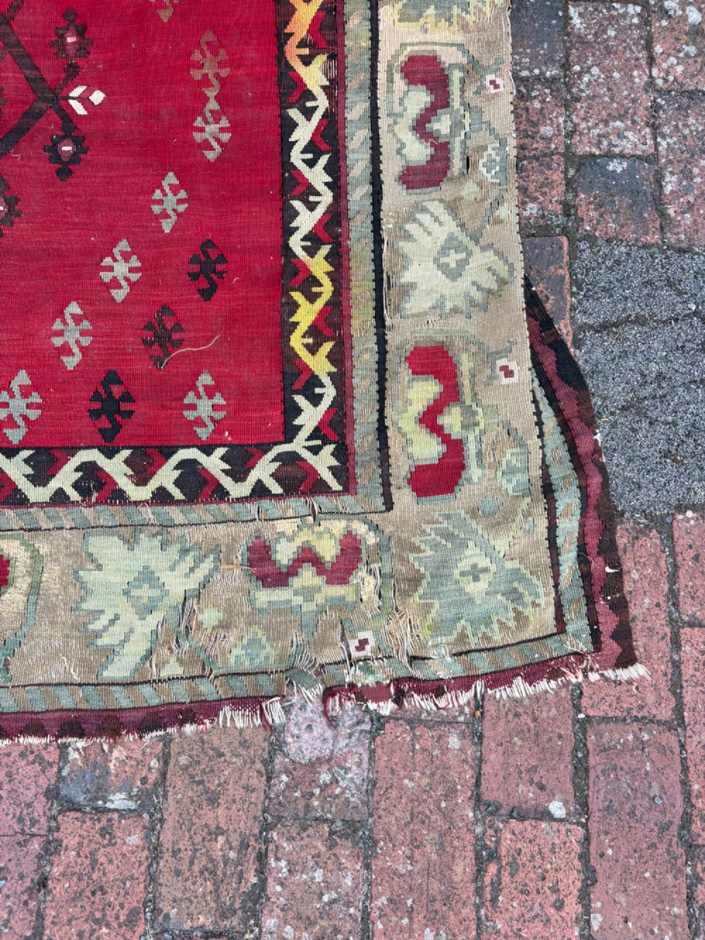 A large handwoven Anatolian flatweave kilim rug featuring a vivid red field patterned with dark geometric diamond motifs and framed by a light beige border. View IX
