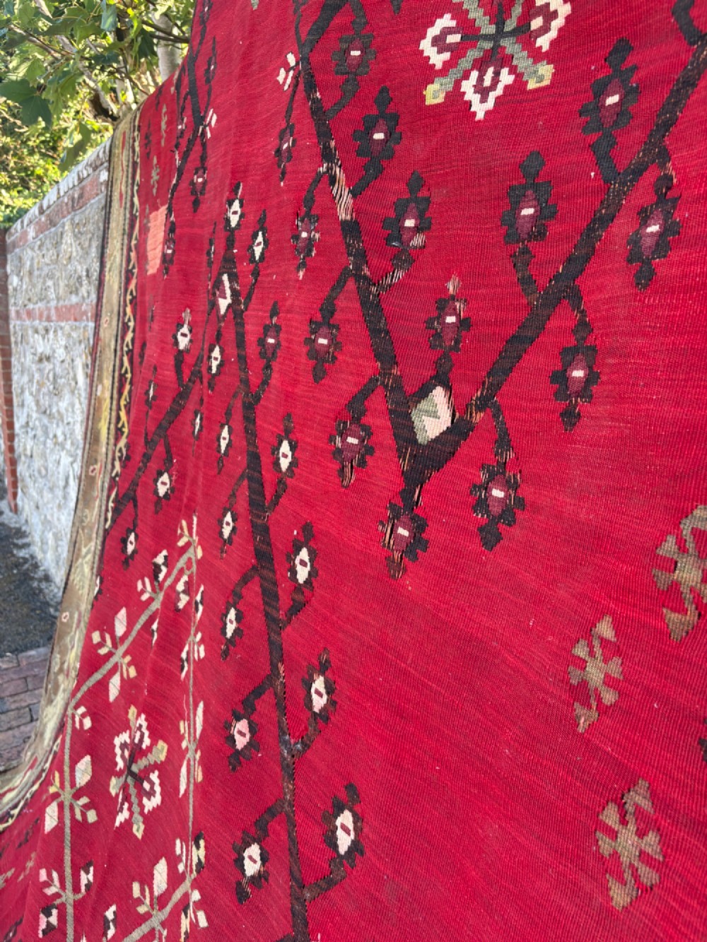 A large handwoven Anatolian flatweave kilim rug featuring a vivid red field patterned with dark geometric diamond motifs and framed by a light beige border. View XI