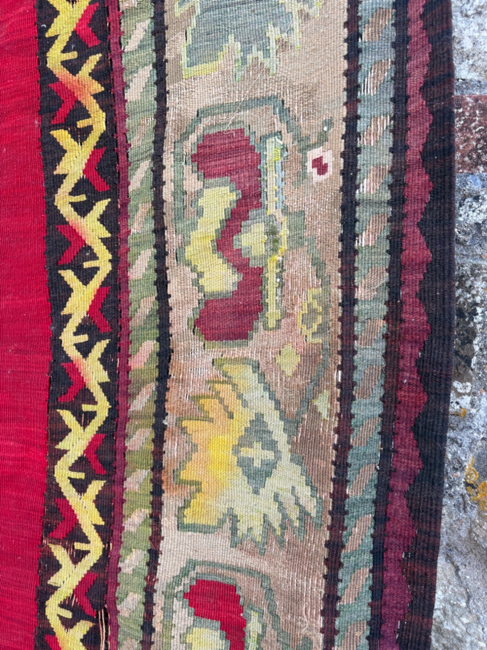 A large handwoven Anatolian flatweave kilim rug featuring a vivid red field patterned with dark geometric diamond motifs and framed by a light beige border. View XII